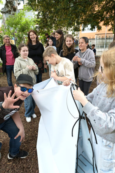 Die Lehrerin Marianne Aselmeyer und die Schüler:innen breiten das Lesezeichen-Banner aus.