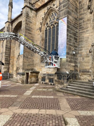 Mit einem Leiterwagen der Feuerwehr wird das Lesezeichen-Banner an der Andreaskirche angebracht.