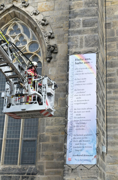 Mit einem Leiterwagen der Feuerwehr wird das Lesezeichen-Banner an der Andreaskirche angebracht.