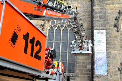 Mit einem Leiterwagen der Feuerwehr wird das Lesezeichen-Banner an der Andreaskirche angebracht.