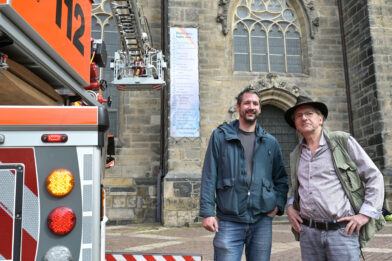 Initiator Jo Köhler und Montageleiter Benjamin Spitzbart posieren vor der Andreaskirche.
